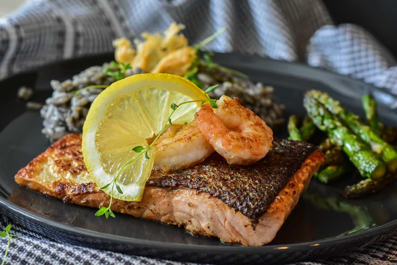 A sheet pan with roasted salmon fillets, asparagus, and lemon slices